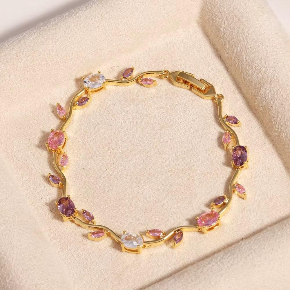 Gold bracelet with floral design stones displayed on beige fabric