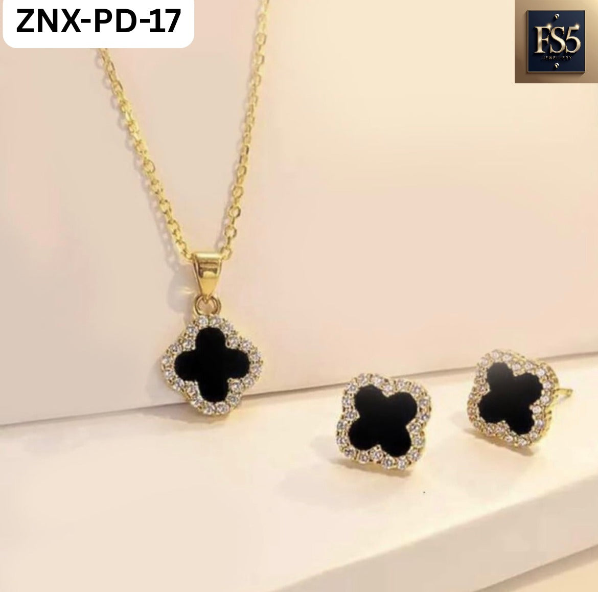 Gold-tone necklace and stud earrings set with black clover-shaped pendants surrounded by clear stones