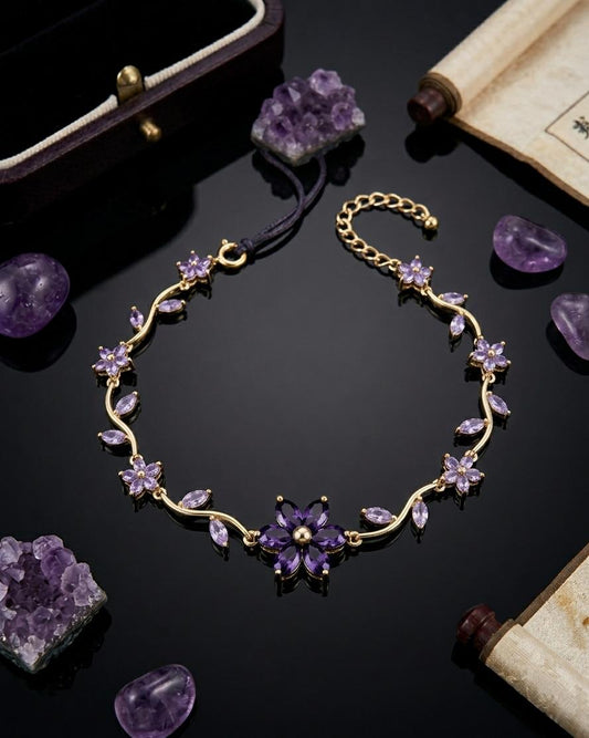 Gold-plated bracelet with amethyst flowers and leaves laid on black surface with amethyst stones