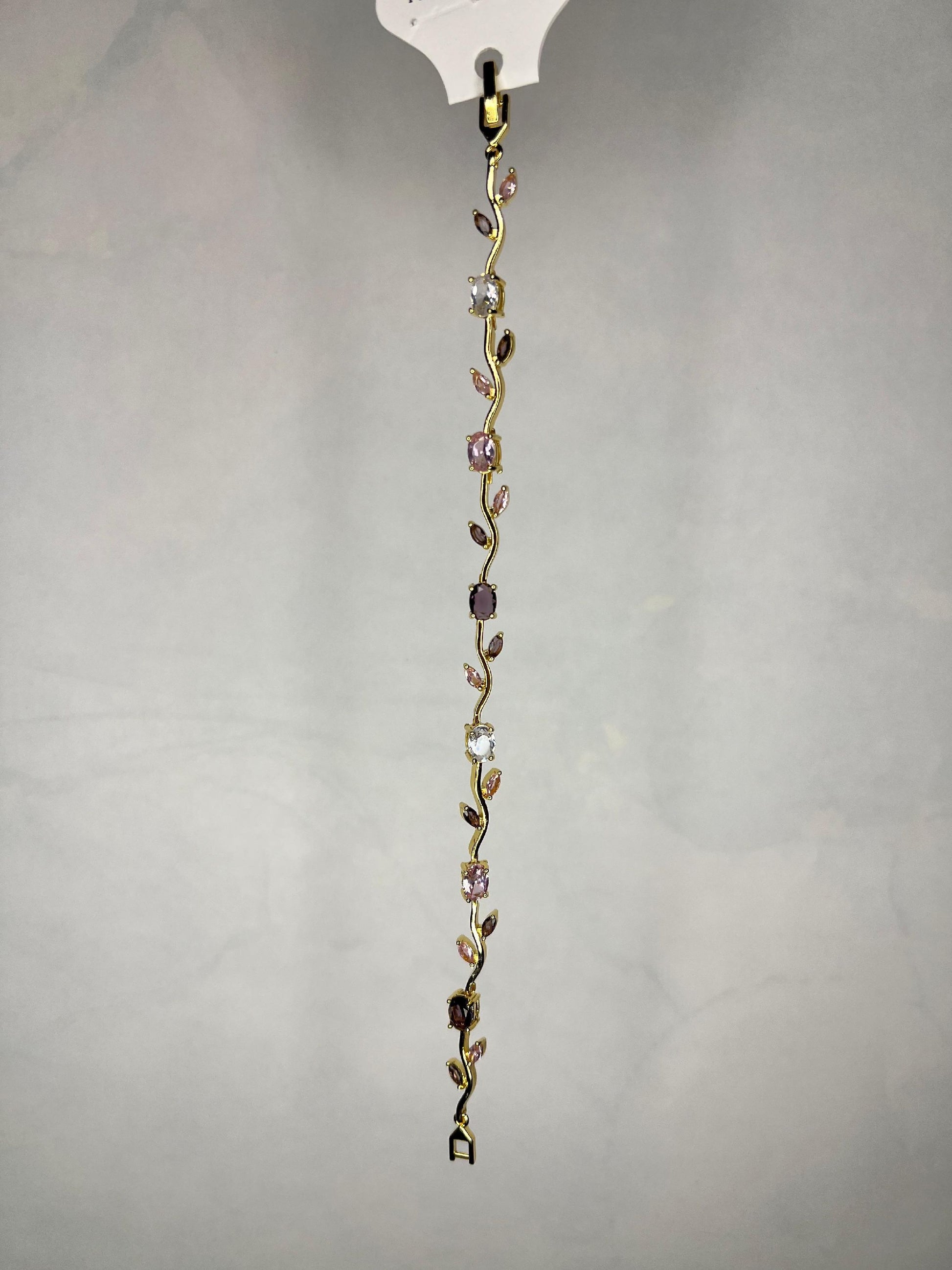 Close-up of elegant gold-tone bracelet with various cut pink and clear stones hanging vertically